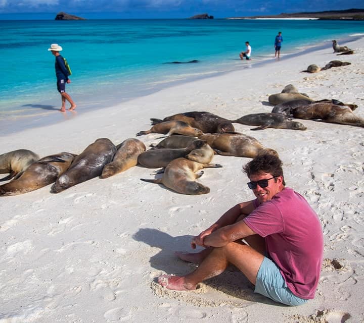 Traveler enjoying a Galapagos white sand beach with sleepy Galapagos sea lions