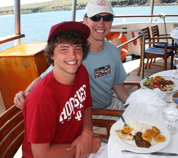 Dad & Son dining aboard M/V Evolution Dad & Son aboard M/V Evolution dining al fresco on a Galapagos Family Cruise