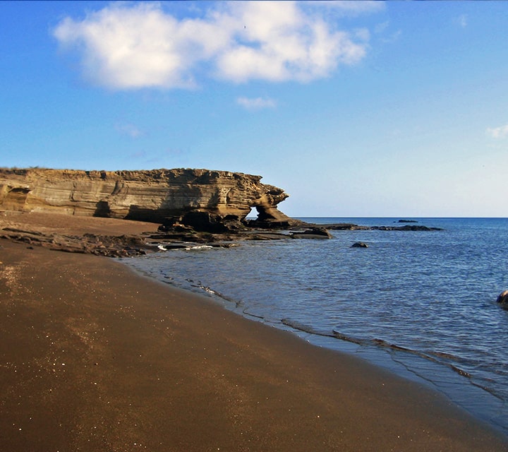 Black sand beach slopes to a rocky sea floor at James Bay on Santiago Island, Galapagos