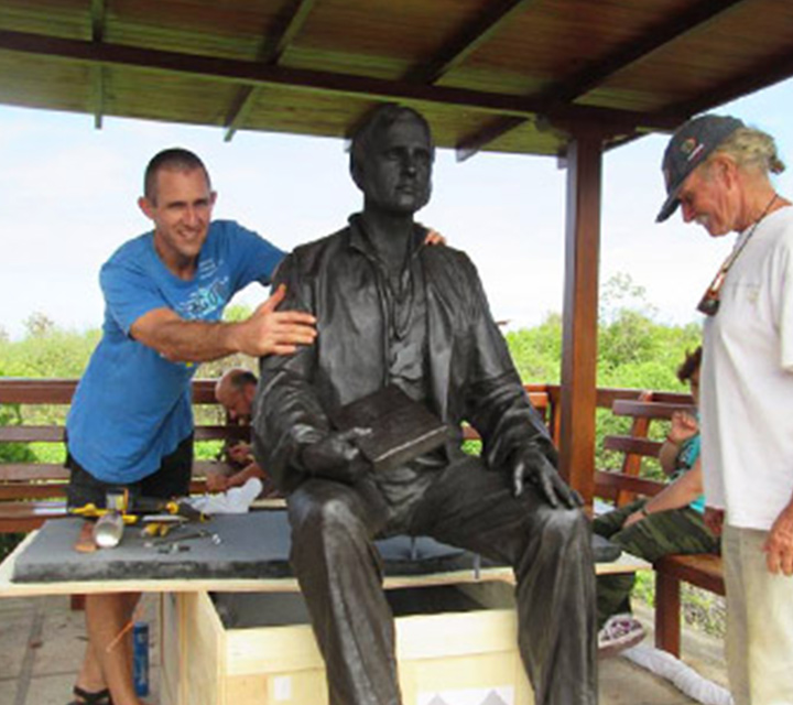 Godfrey Merlen standing next to the Charles Darwin Statue in the Galapagos Islands
