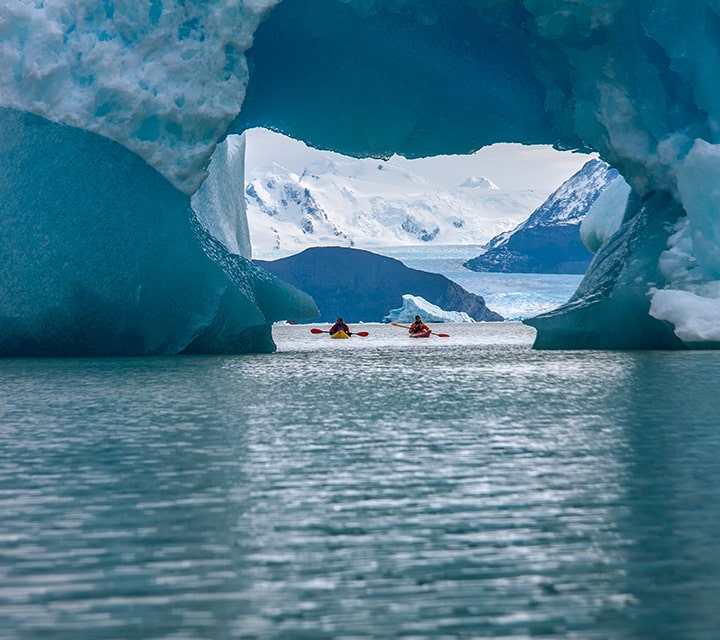 Kayakers at a distance view point from glacier on lake in Patagonia