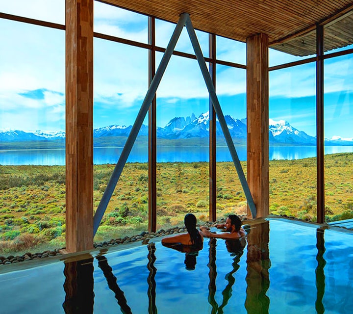 A couple in an indoor infinity pool looking out towards Torres del Paine National Park, Chile