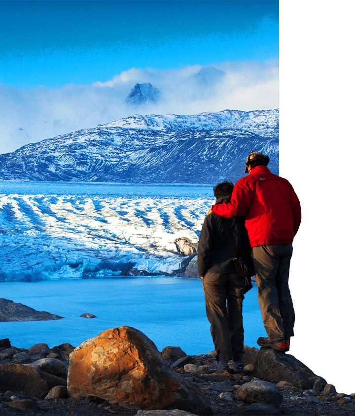 A couple standing on the cliffside looking out at the glacial ice fields in Patagonia
