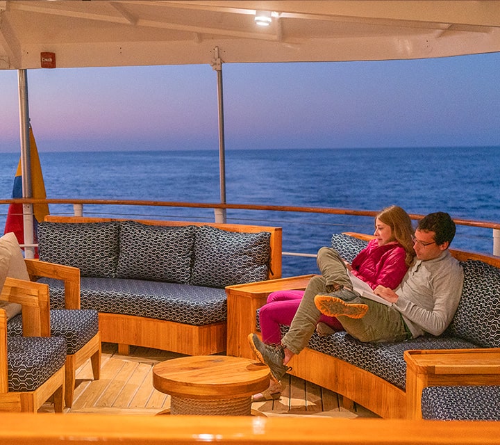 A couple lounging on Evolution Yacht A couple lounging on the upper deck of Quasar's luxury Evolution yacht on a 8-day cruise