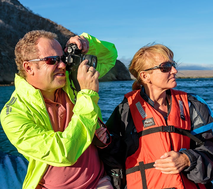A couple taking pictures of Galapagos scenery while on dinghy panga ride