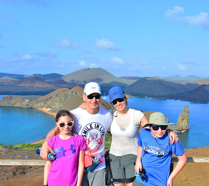 A family of four posing for a photo atop the summit of Bartolome Island, Galapagos