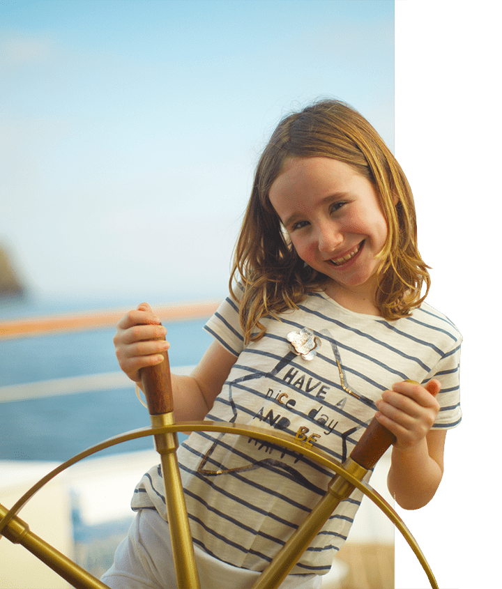 Girl behind ship wheel aboard the Grace Yacht