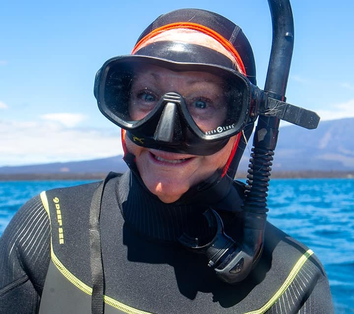 Woman wearing snorkeling gear with the ocean in the background