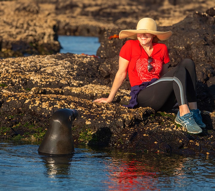Traveler sitting next to Galapagos Sea Lion
