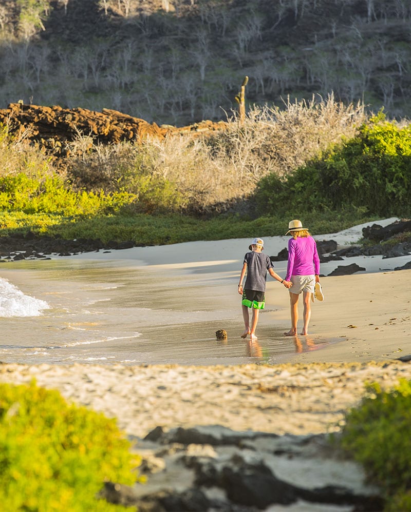 Mother and son walking a Galapagos beach