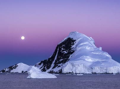 Moonrise over a snowy peak in Antarctica