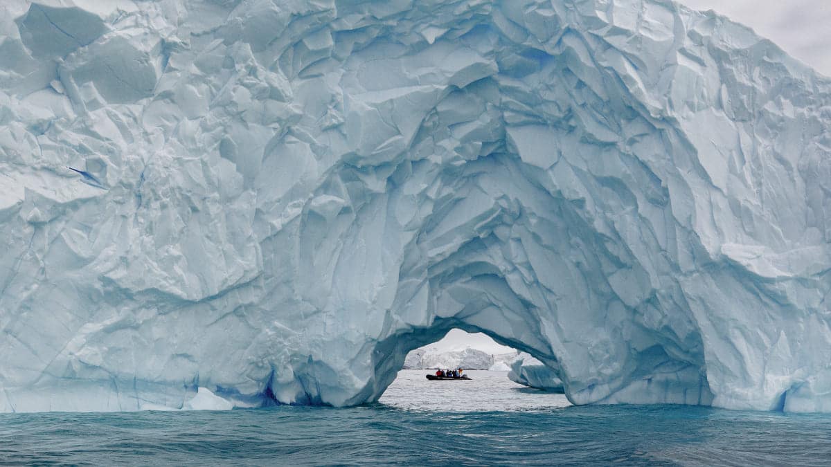 Zodiac under iceberg arch in Antarctica Zodiac under iceberg arch in Antarctica
